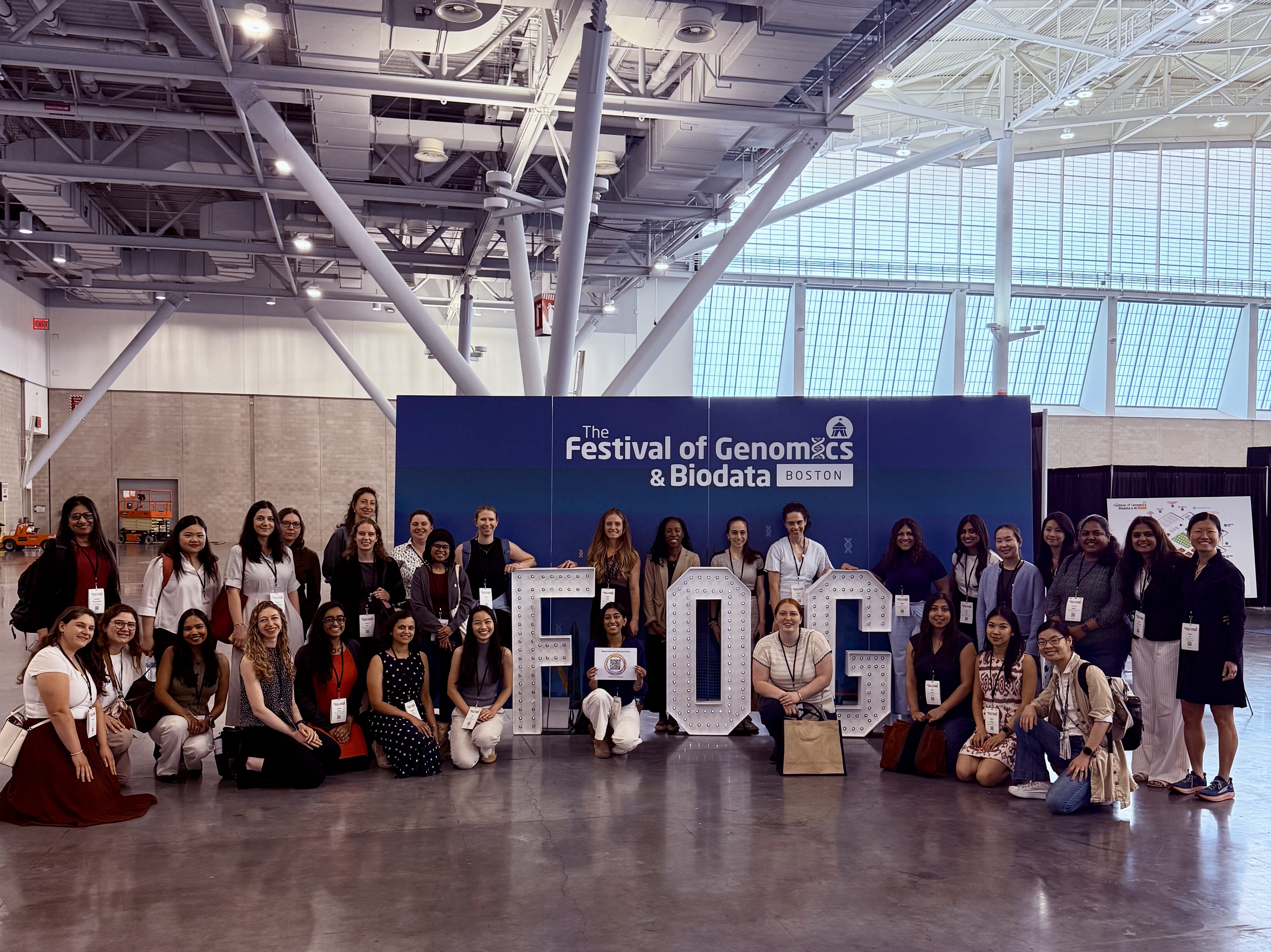 Attendees of Boston Women in Bioinformatics networking event in front of Festival of Genomics backdrop